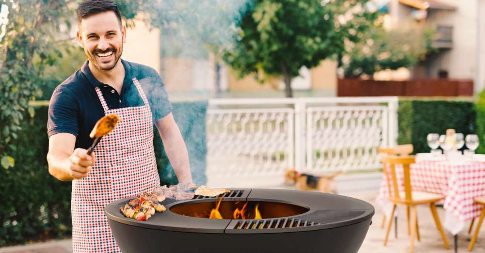 Homme avec tablier cuisine sur un BBQ, gril. Comment tenir le meilleur BBQ de distanciation sociale de l’été!