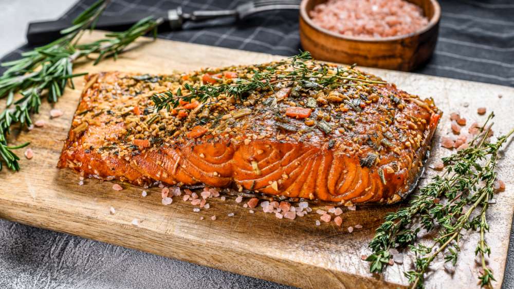 Saumon fumé lentement à basse température avec herbes et épices sur planche à découper en bois. Low and slow.
