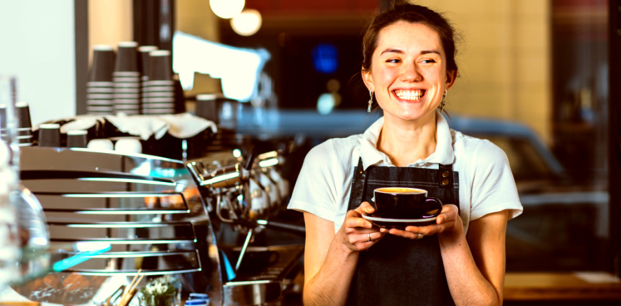 Comment développer une attitude Hygge en 5 étapes, jeune femme barista qui sourit, profiter des petits moments