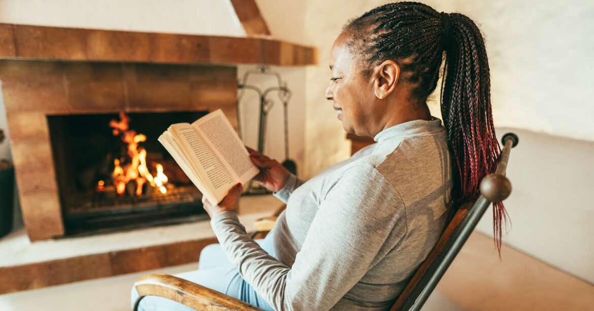 20 Activités Chaleureuses Près du foyer pour le Plaisir et la Détente en Hiver- une femme lit au bord du feu