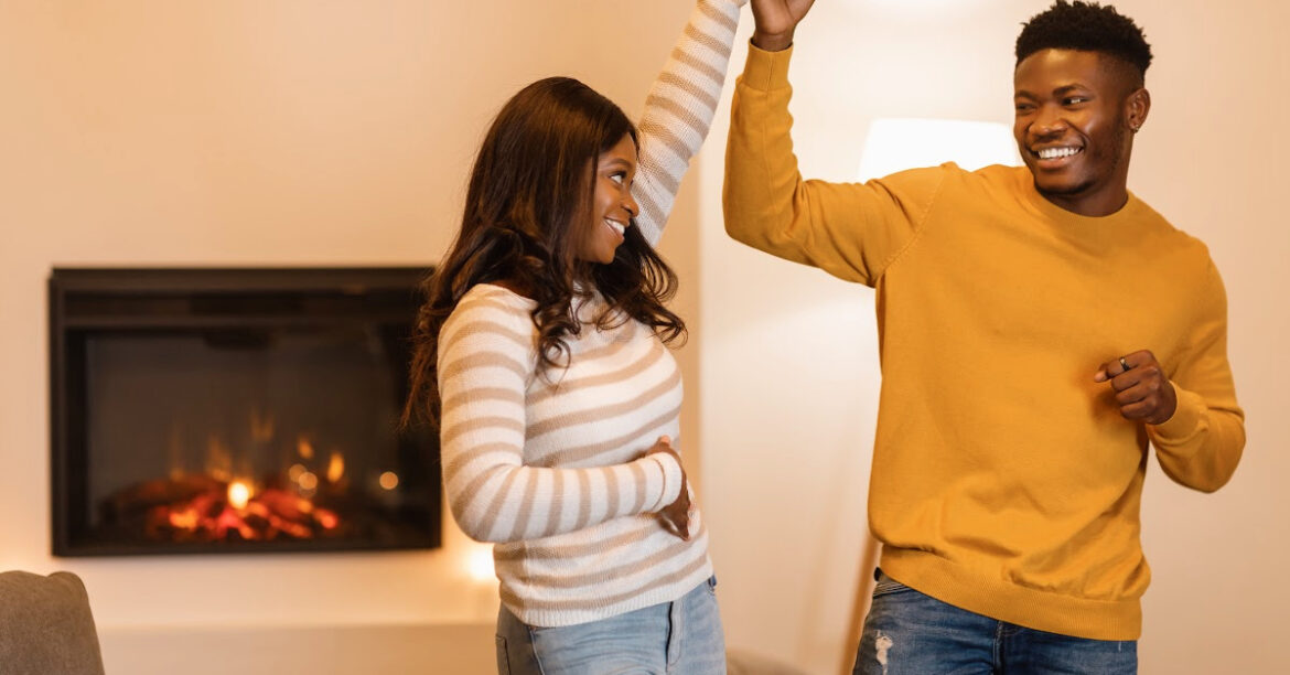 La Romance de l'Hiver : Idées de Soirées en Amoureux au Coin du Foyer- un couple danse au bord du feu